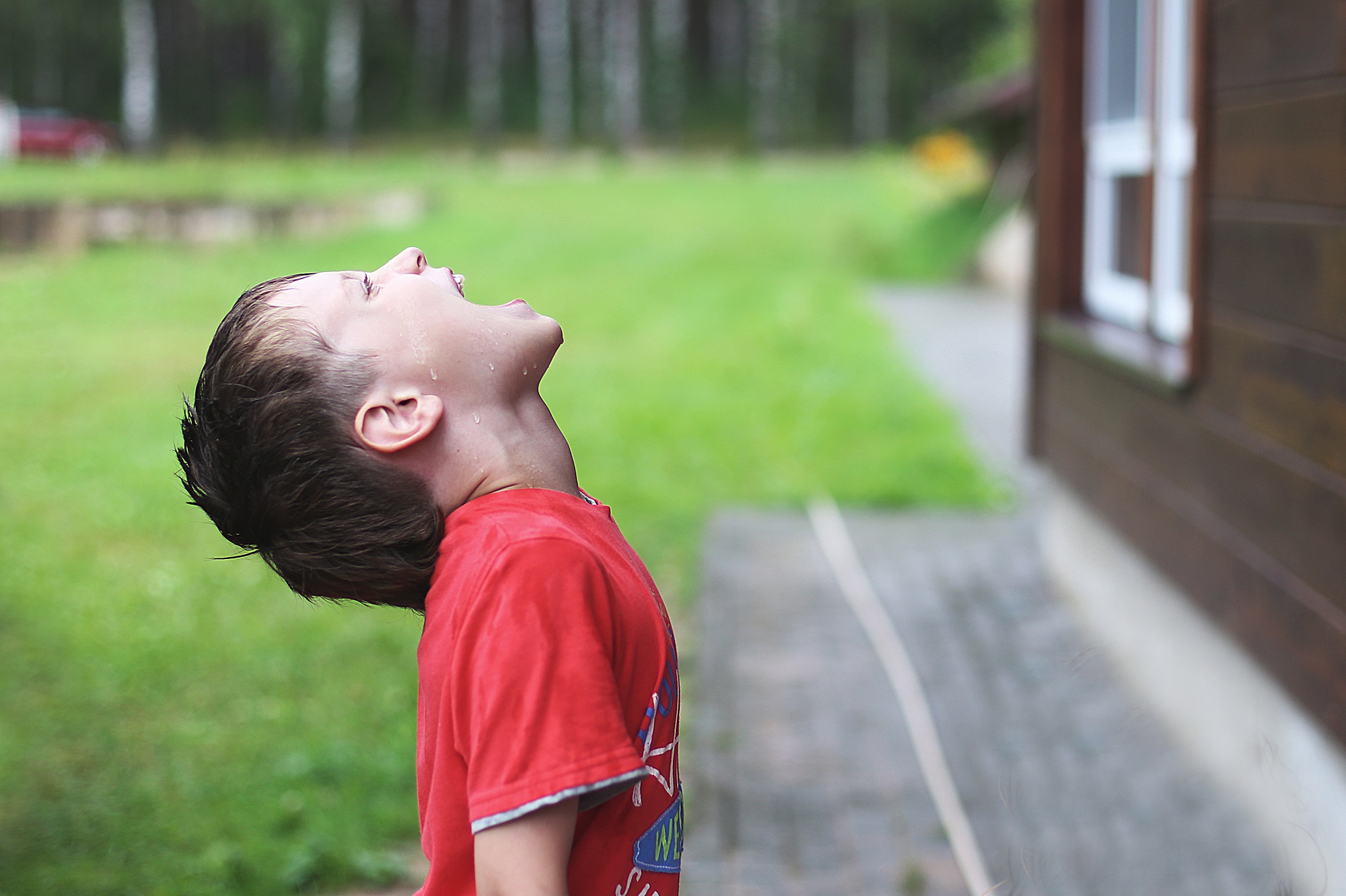 Child jumping in puddle and mud in the rain.