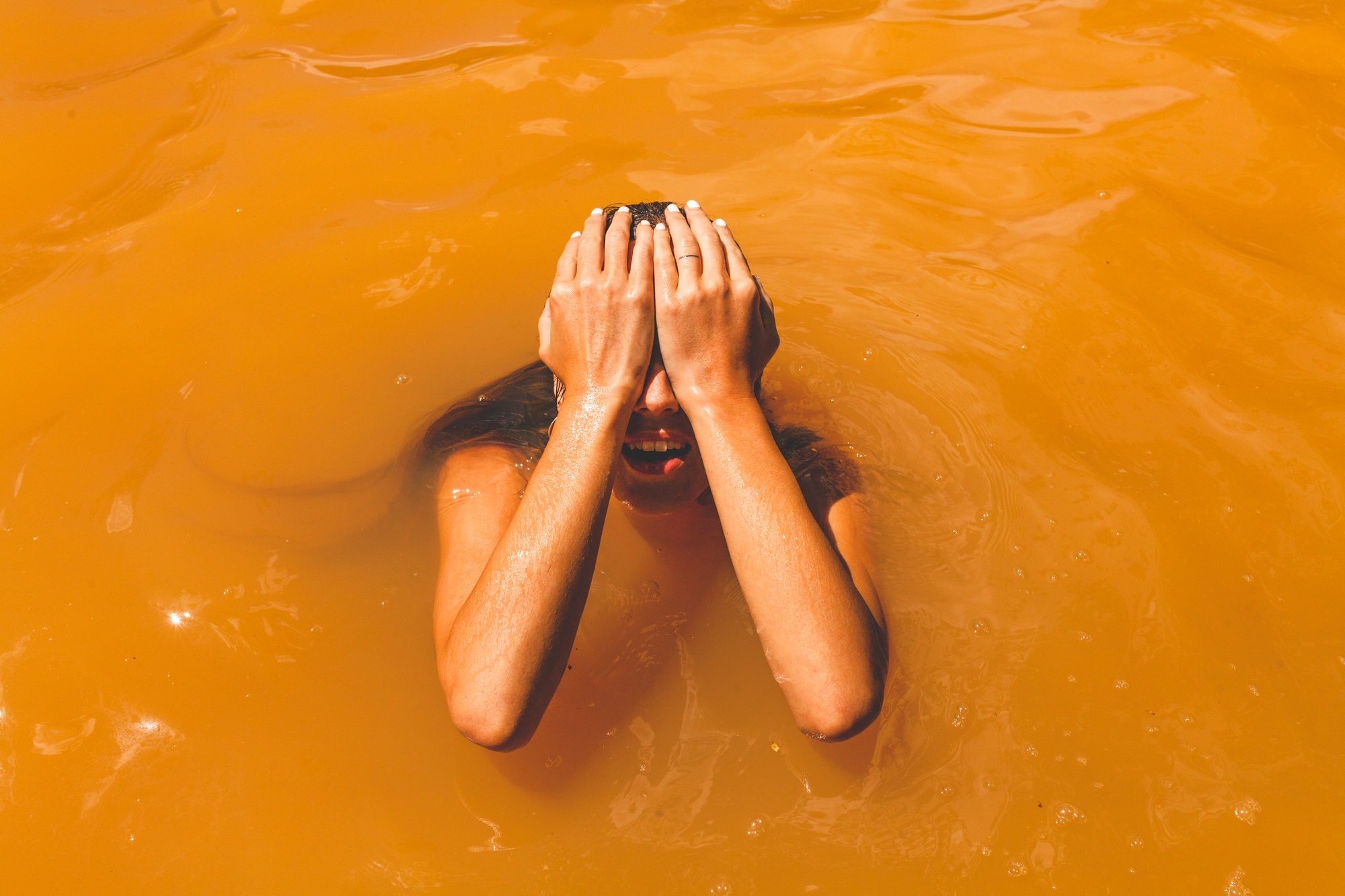 Smiling woman swimming in resort mud pool