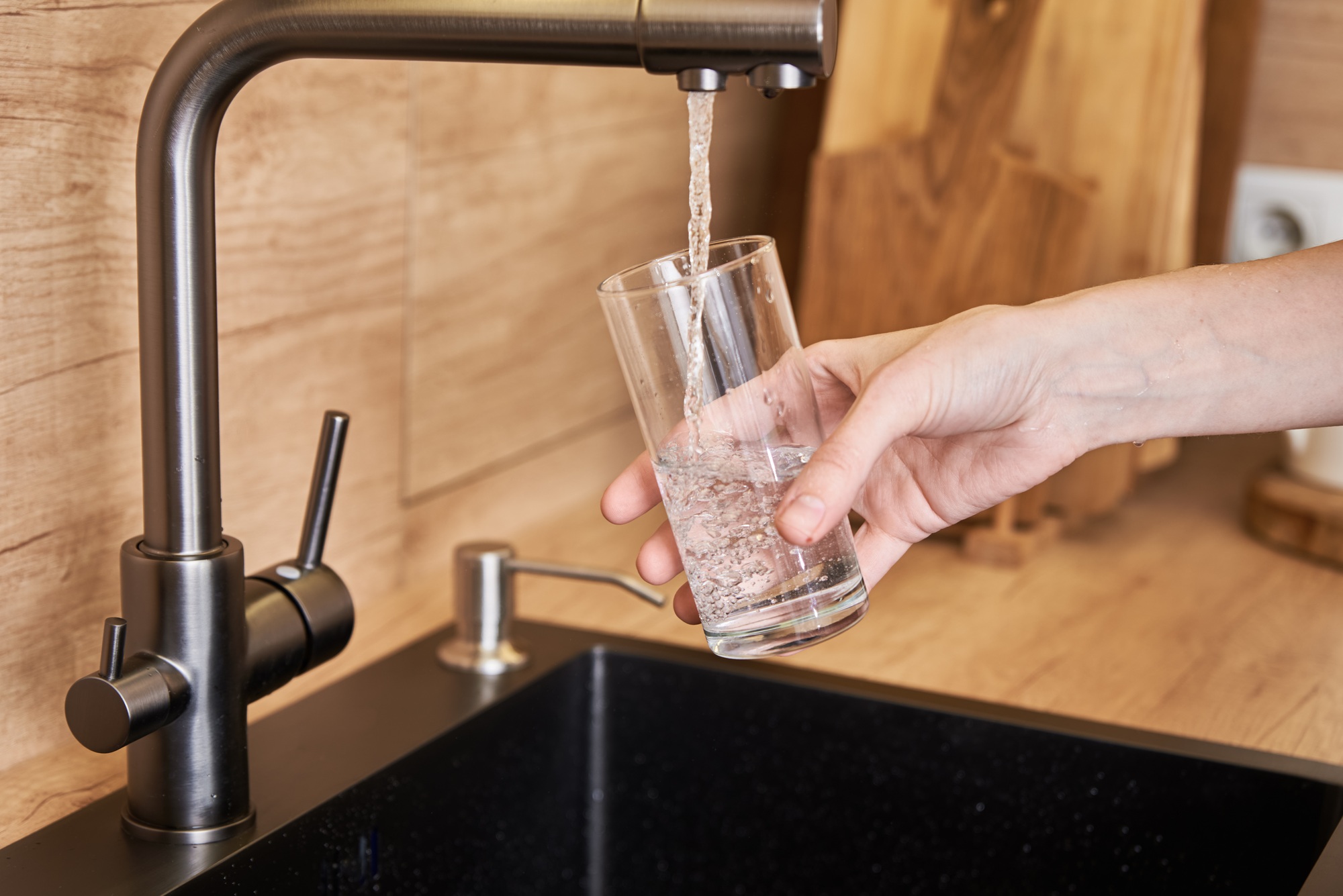 Woman pour clean water from tap filter into a glass