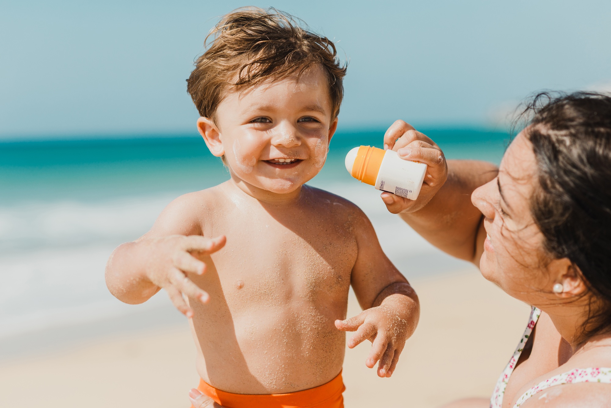Mother applying sunscreen cream to baby