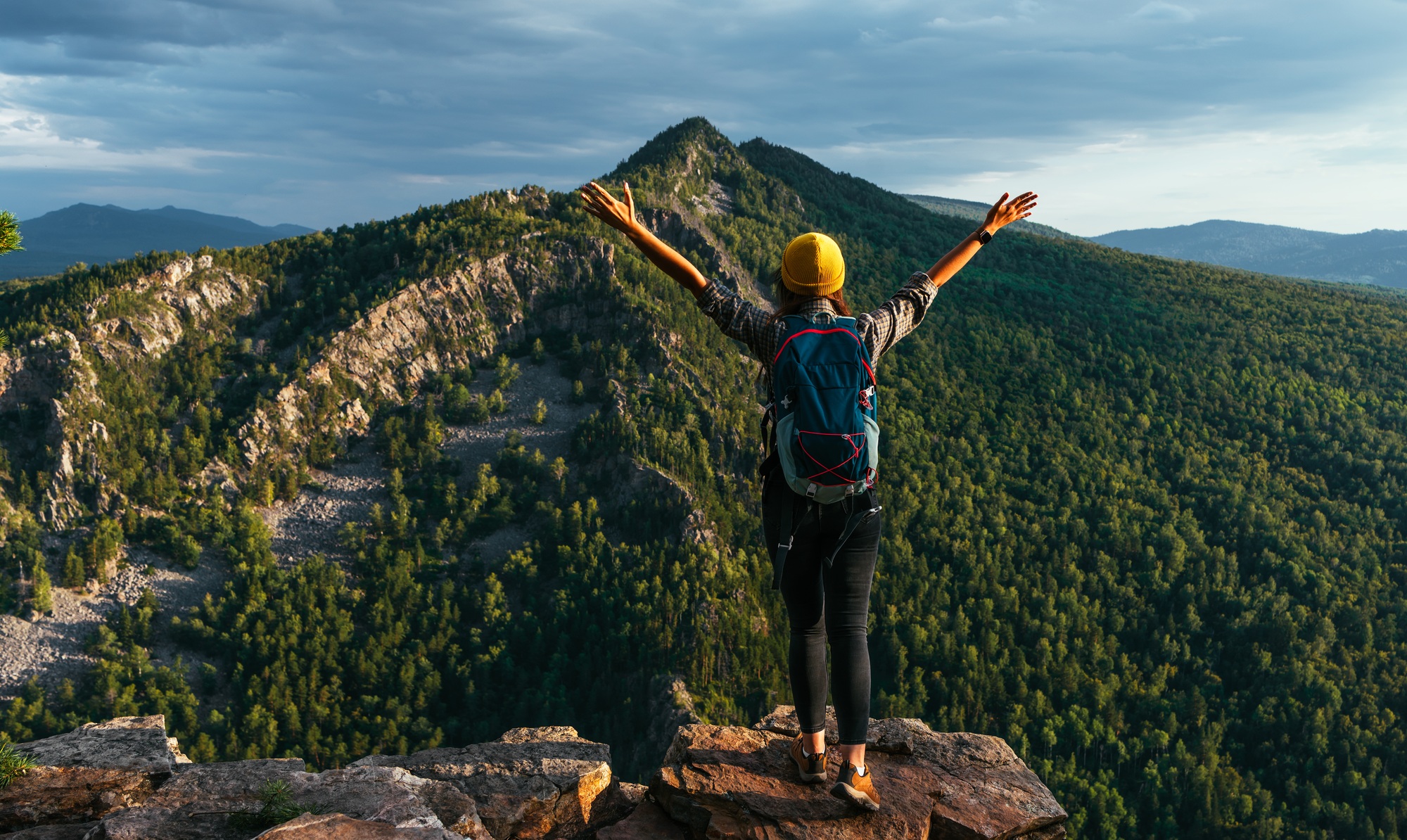 A lonely traveler with a backpack on the background of mountains, panorama